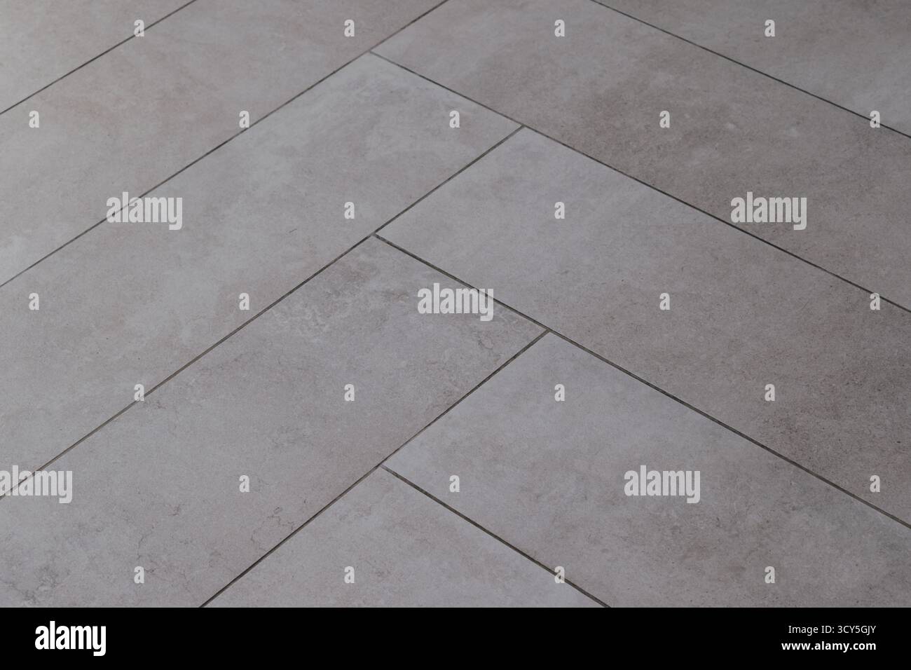 Grey rectangular tile texture in herringbone pattern imitating natural stone. Stock Photo