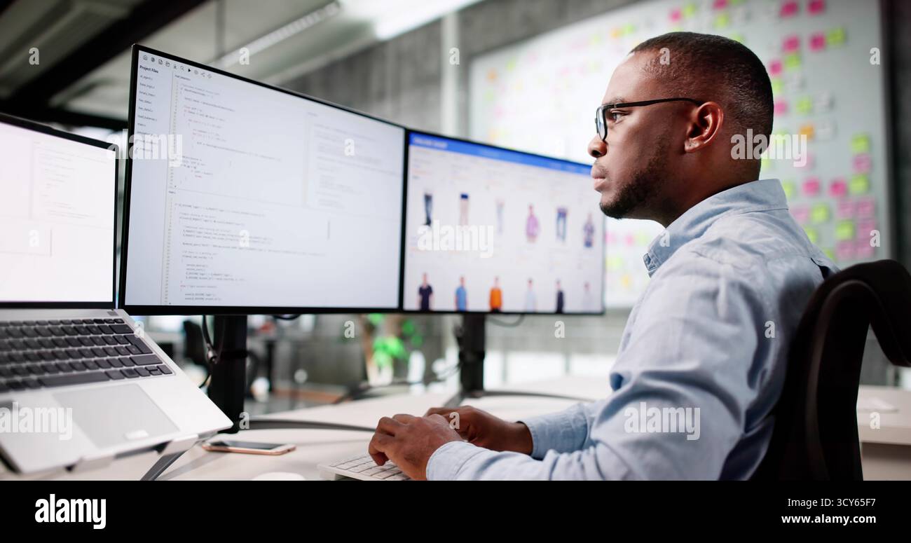 African American Man Coding Ecommerce Software On Multiple Office Monitors. Stock Photo