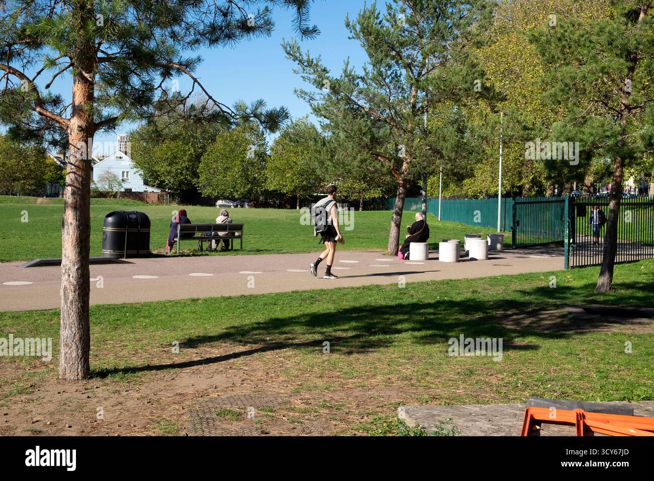 People enjoying sunshine sunny day in Queen Elizabeth Olympic Park in autumn October man walking along path Newham Stratford London UK KATHY DEWITT Stock Photo