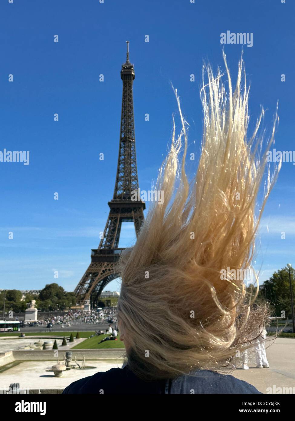 View from the Trocadéro of woman blonde hair blowing in the wind with Eiffel Tower as a back drop - Smartphone Captured Stock Image