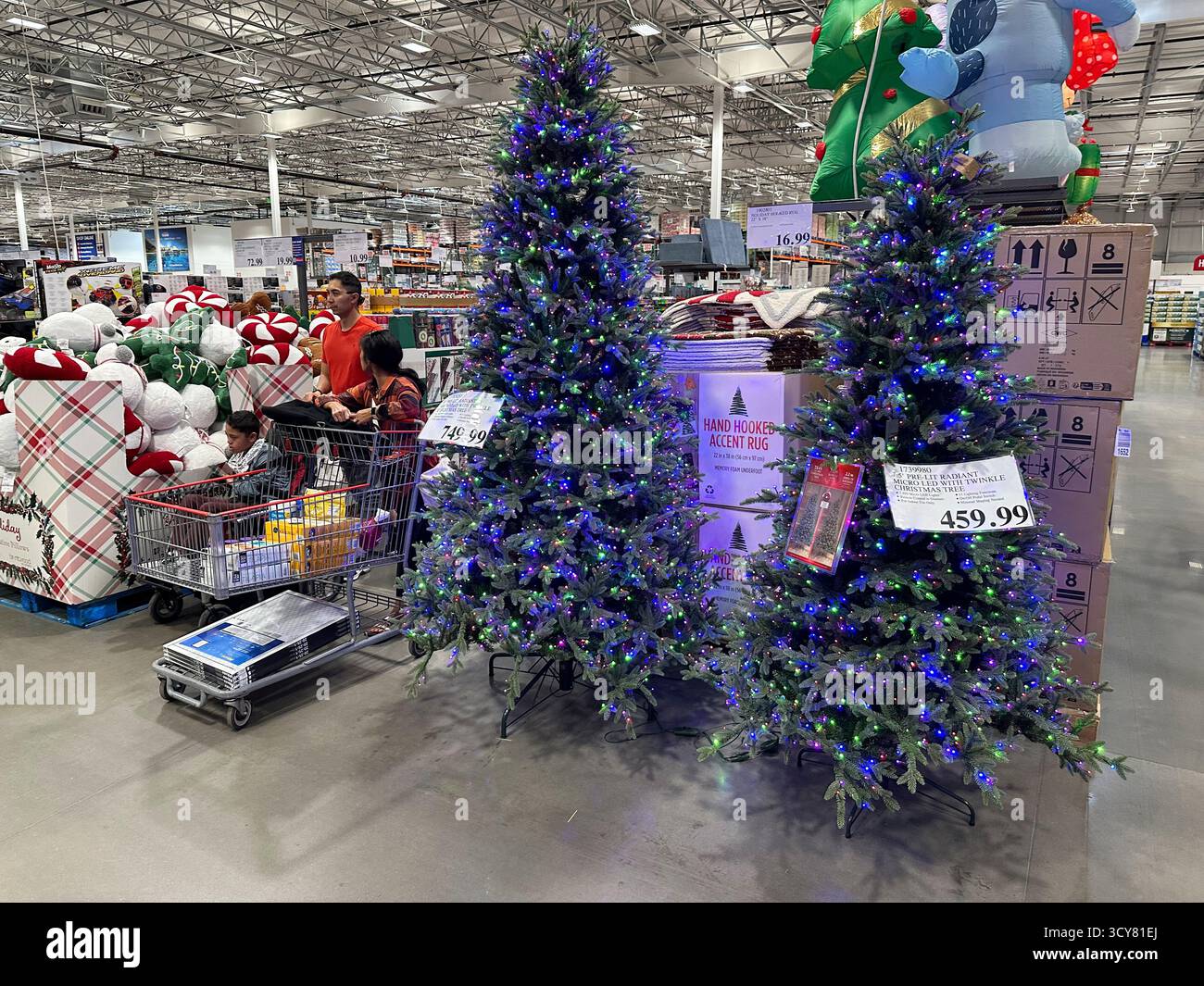 Shoppers pass by holiday trees on display in a Costco warehouse Tuesday ...