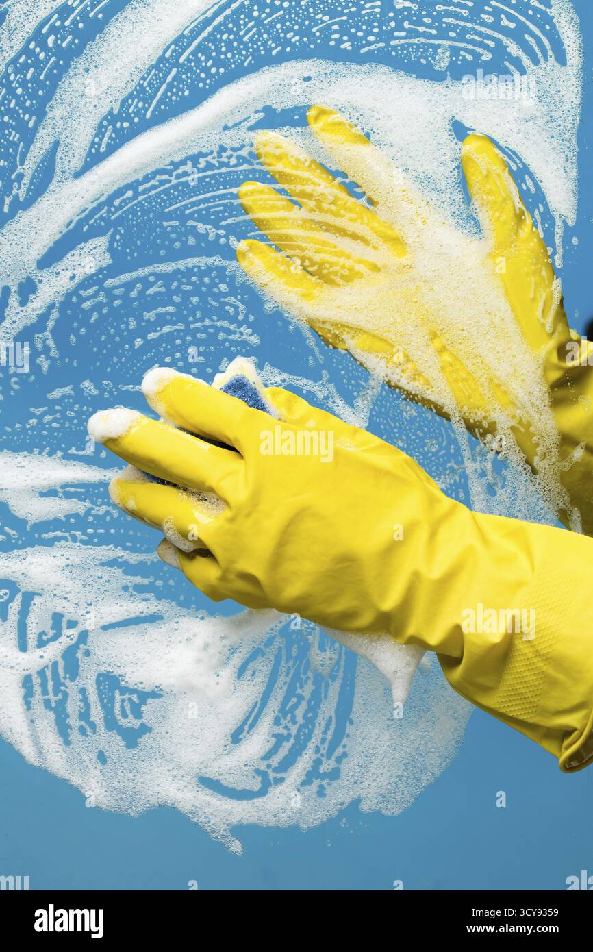 Person washes window with foam on blue background Stock Photo