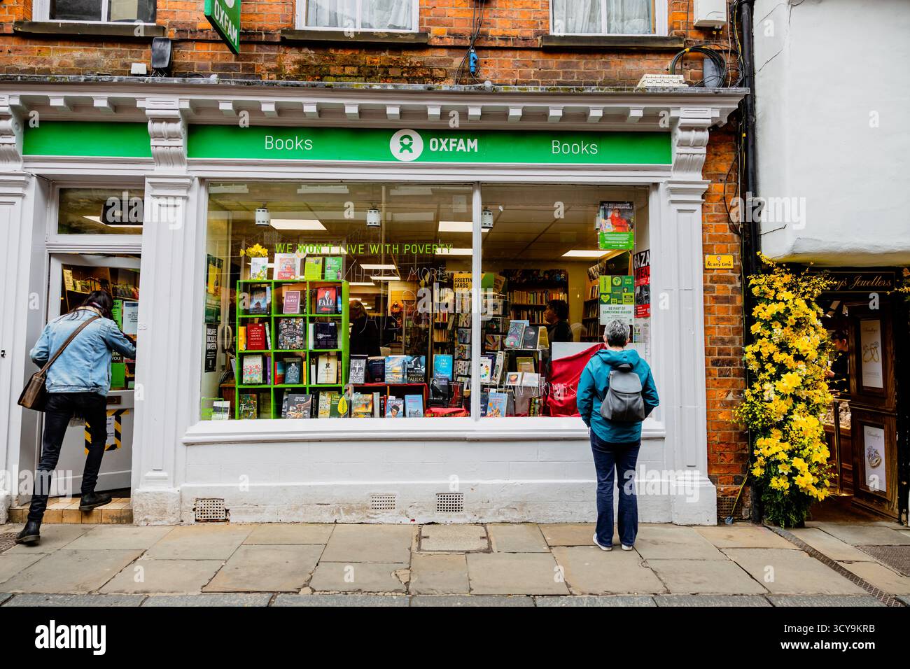 woman standing outside of the Oxfam Bookstore store front looking at the display in the window, city of York Stock Photo