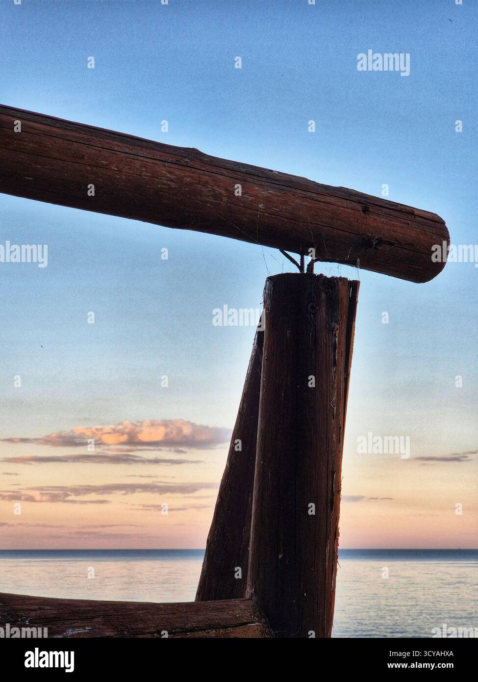 pink sunset in the sky. view of the sea through a wooden structure. - Smartphone Captured Stock Image