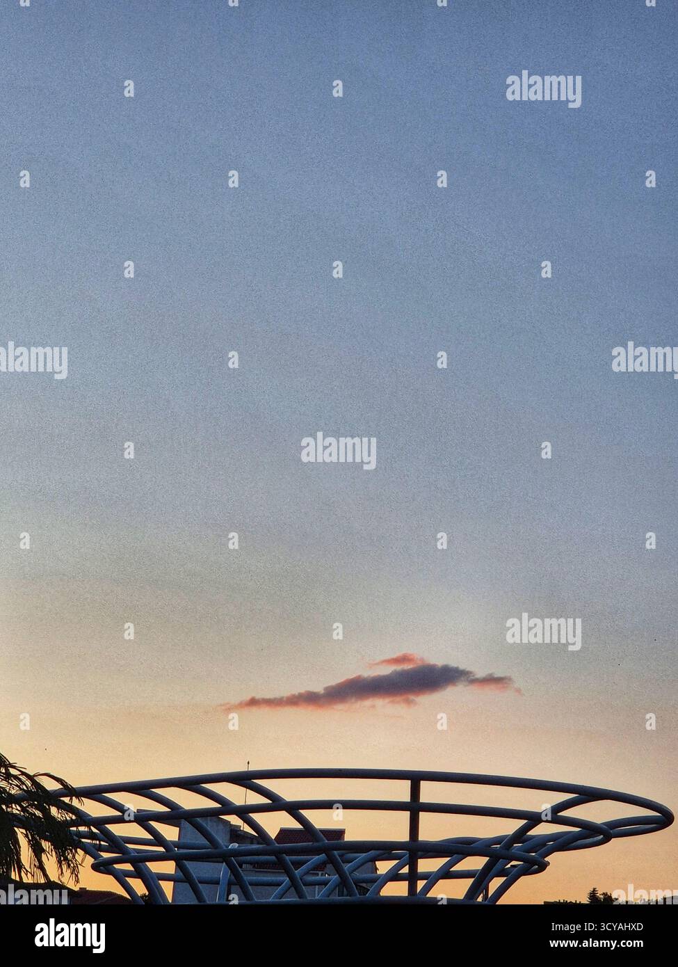 sunset in the sky. unusual cloud over modern architectural structure - Smartphone Captured Stock Image