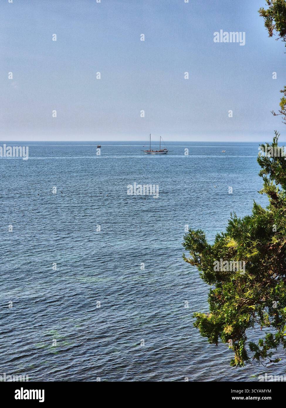 Endless blue expanse of water under a bright sky. Calm seascape with distant city silhouette on the horizon - Smartphone Captured Stock Image
