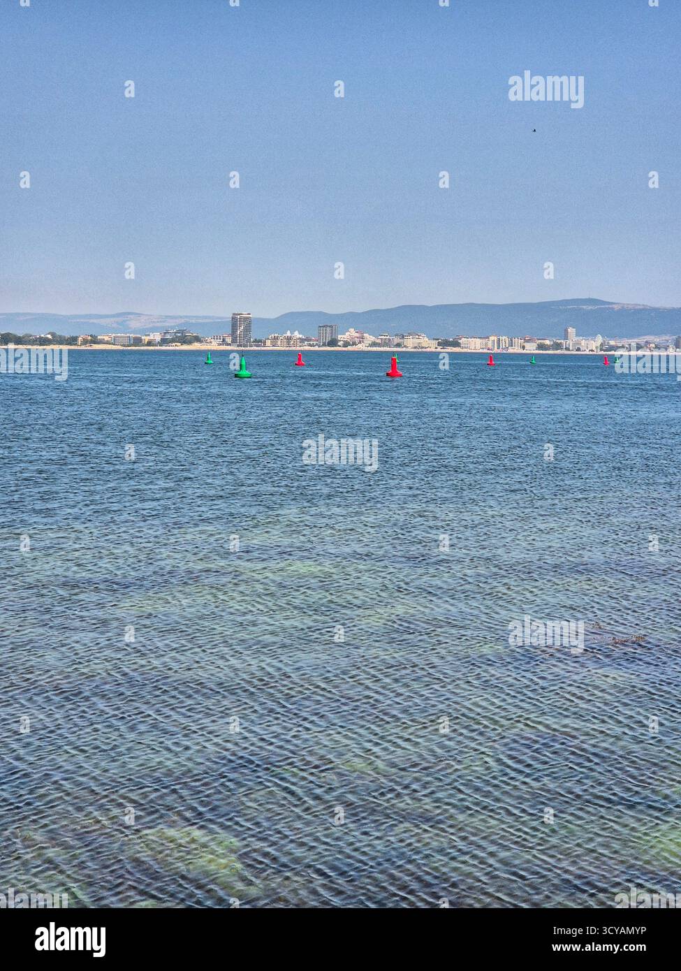 Endless blue expanse of water under a bright sky. Calm seascape with distant city silhouette on the horizon - Smartphone Captured Stock Image