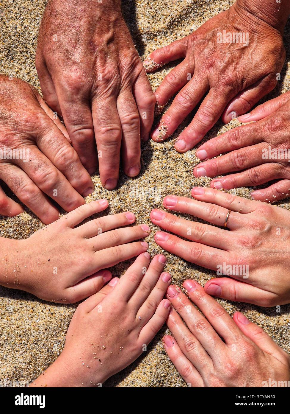 in the frame hands of different generations. hands on the sand. family time. - Smartphone Captured Stock Image