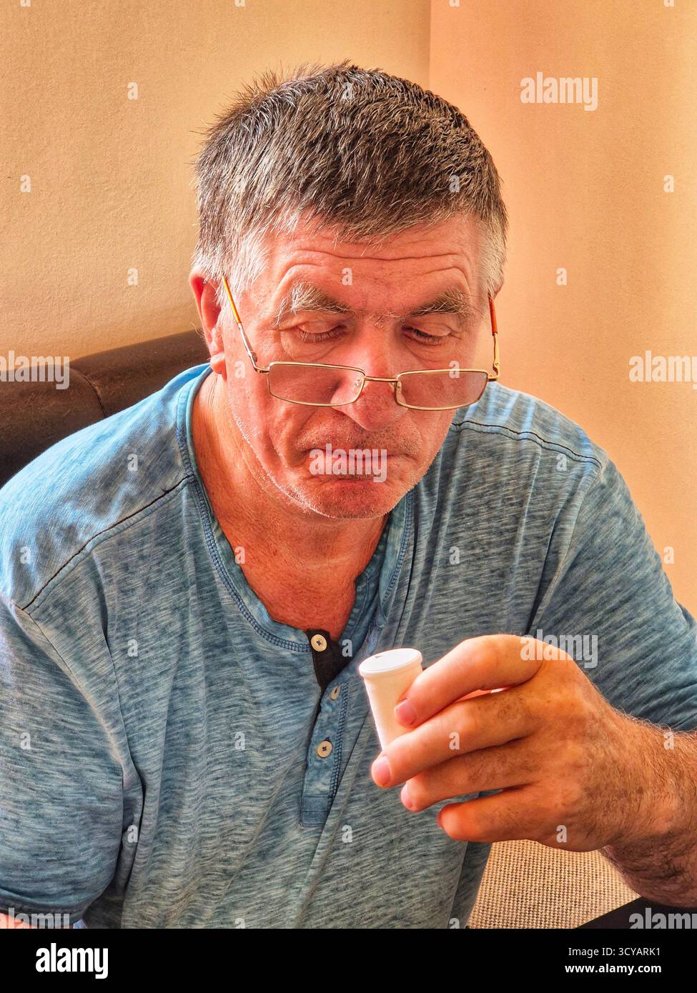 A man carefully examines the instructions and packaging of medication, holding a jar of pills in his hand - Smartphone Captured Stock Image