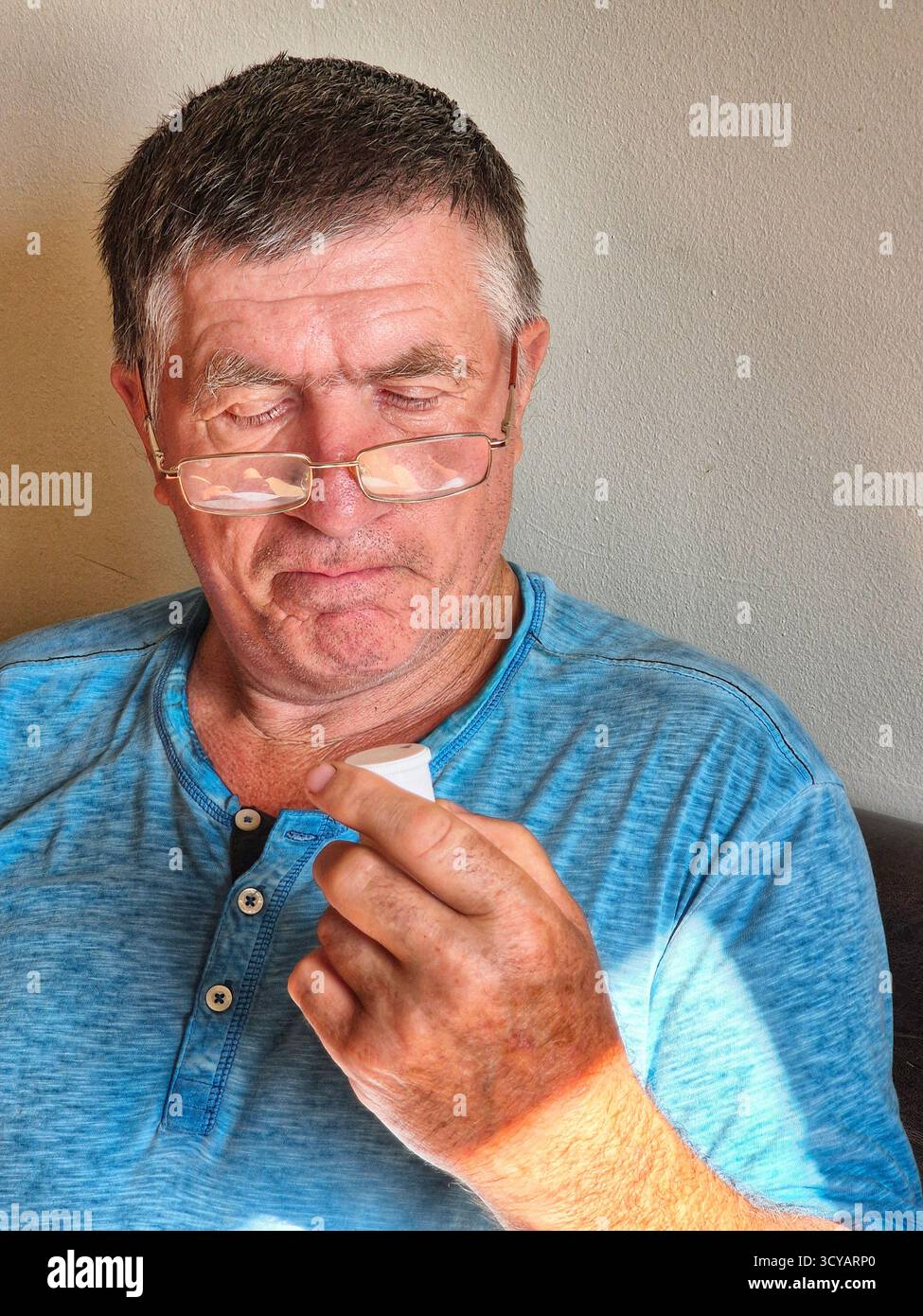 A man carefully examines the instructions and packaging of medication, holding a jar of pills in his hand - Smartphone Captured Stock Image