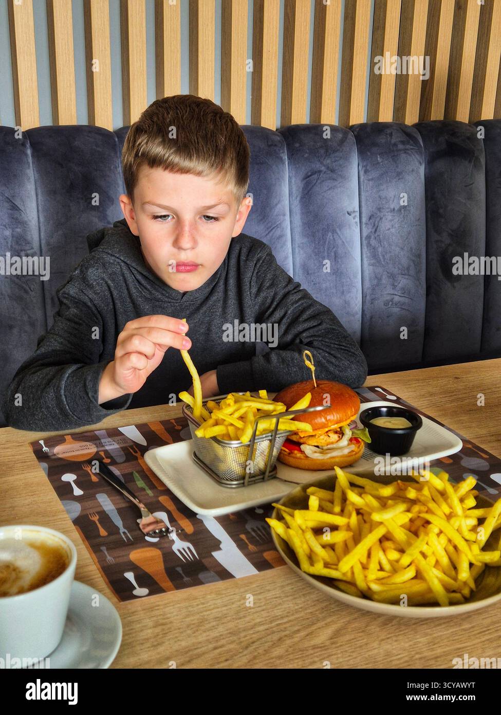 boy eating burger and fries - Smartphone Captured Stock Image