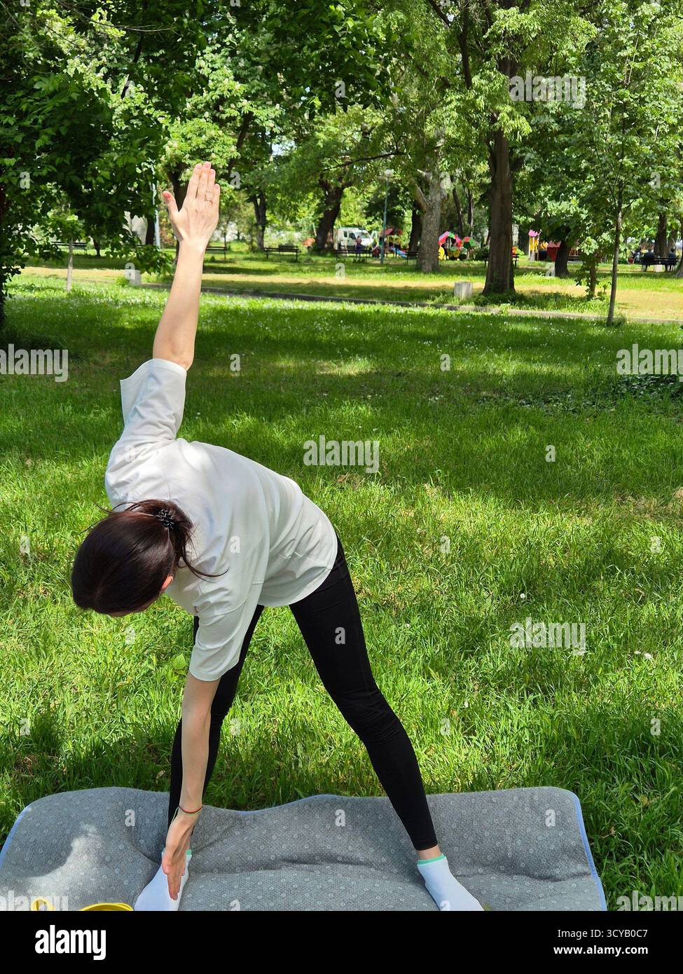 Young woman doing fitness or yoga outdoors in the park. - Smartphone Captured Stock Image
