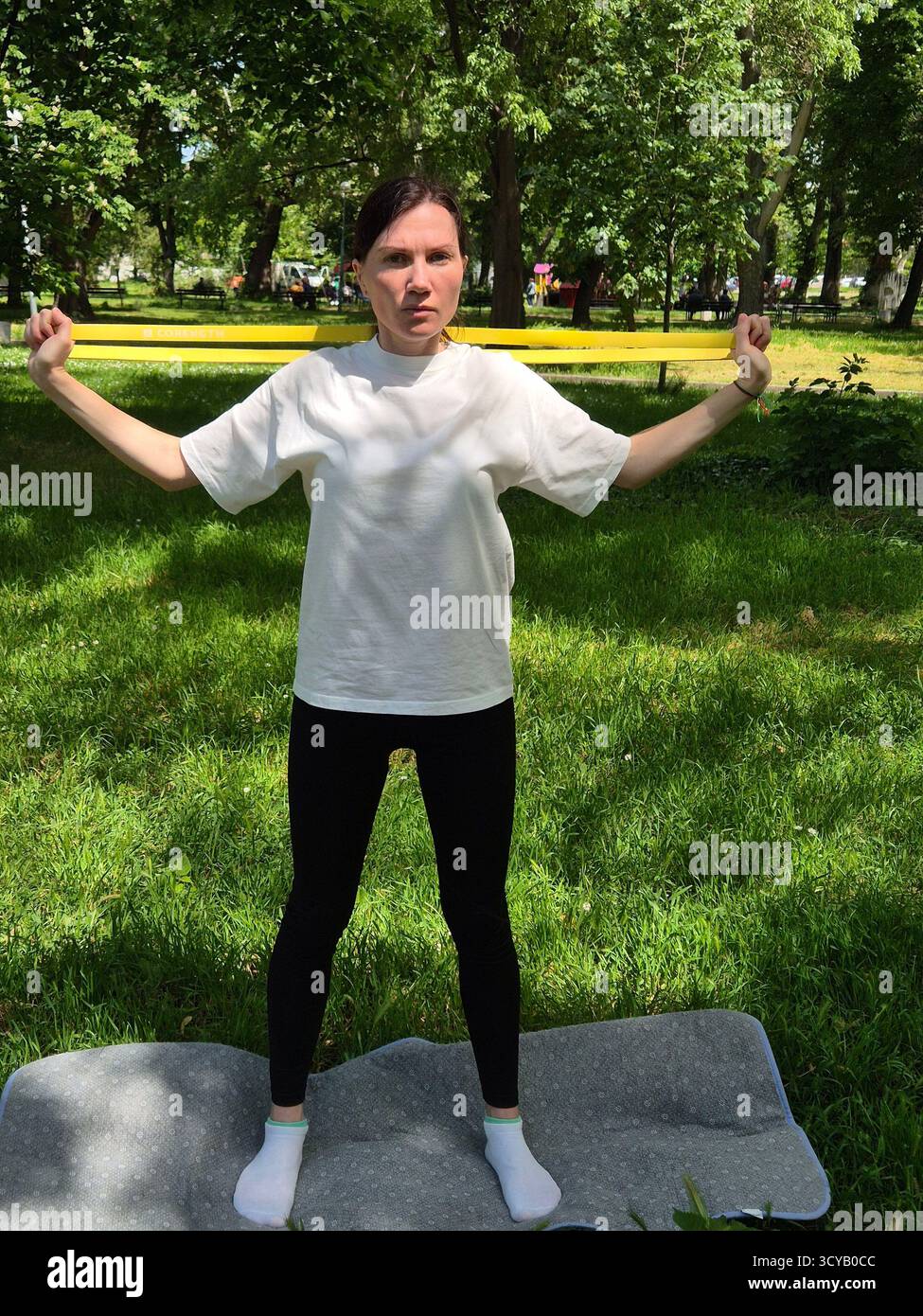 Young woman doing fitness or yoga outdoors in the park. - Smartphone Captured Stock Image