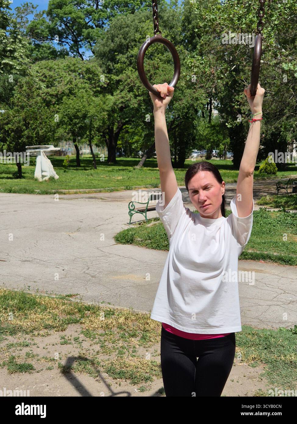 Young woman doing fitness or yoga outdoors in the park. - Smartphone Captured Stock Image