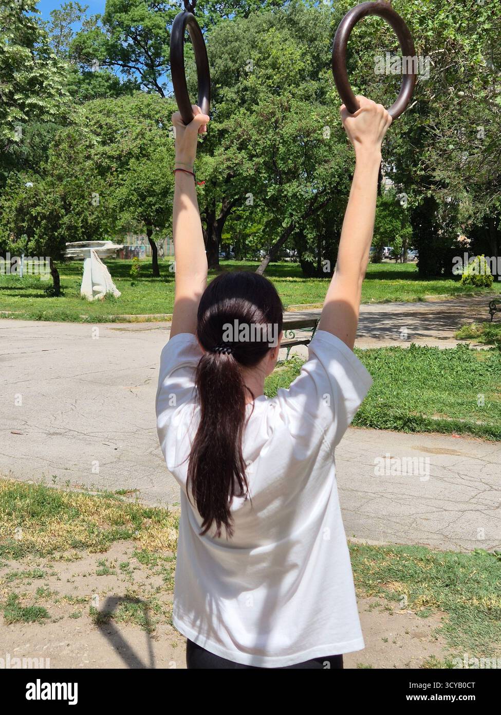 Young woman doing fitness or yoga outdoors in the park. - Smartphone Captured Stock Image