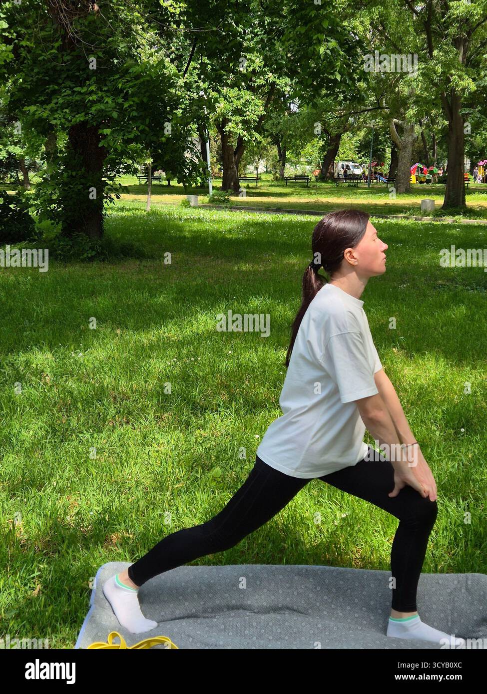 Young woman doing fitness or yoga outdoors in the park. - Smartphone Captured Stock Image