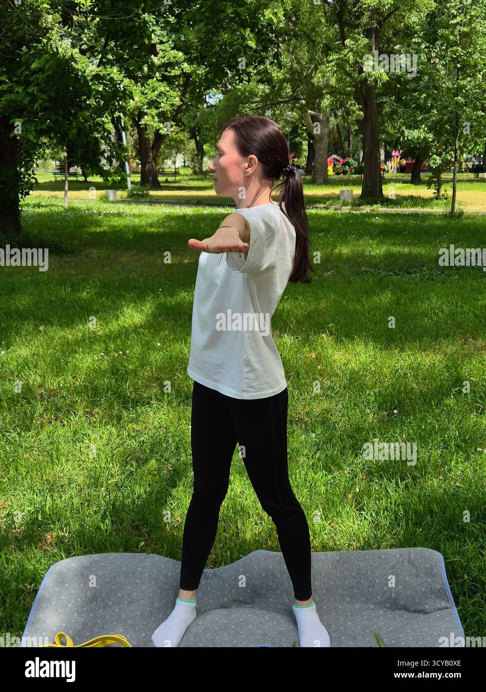 Young woman doing fitness or yoga outdoors in the park. - Smartphone Captured Stock Image