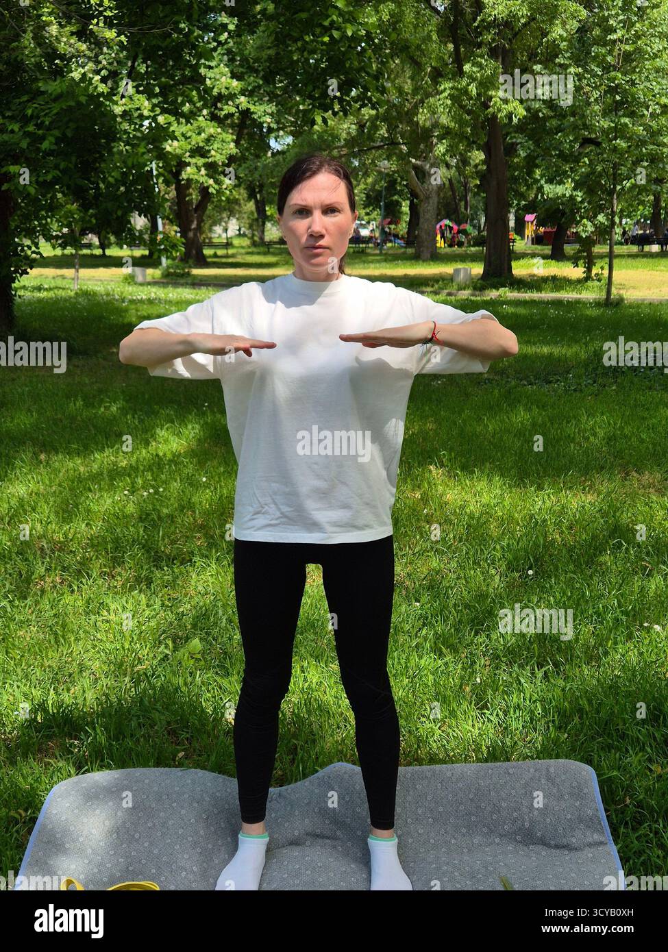 Young woman doing fitness or yoga outdoors in the park. - Smartphone Captured Stock Image