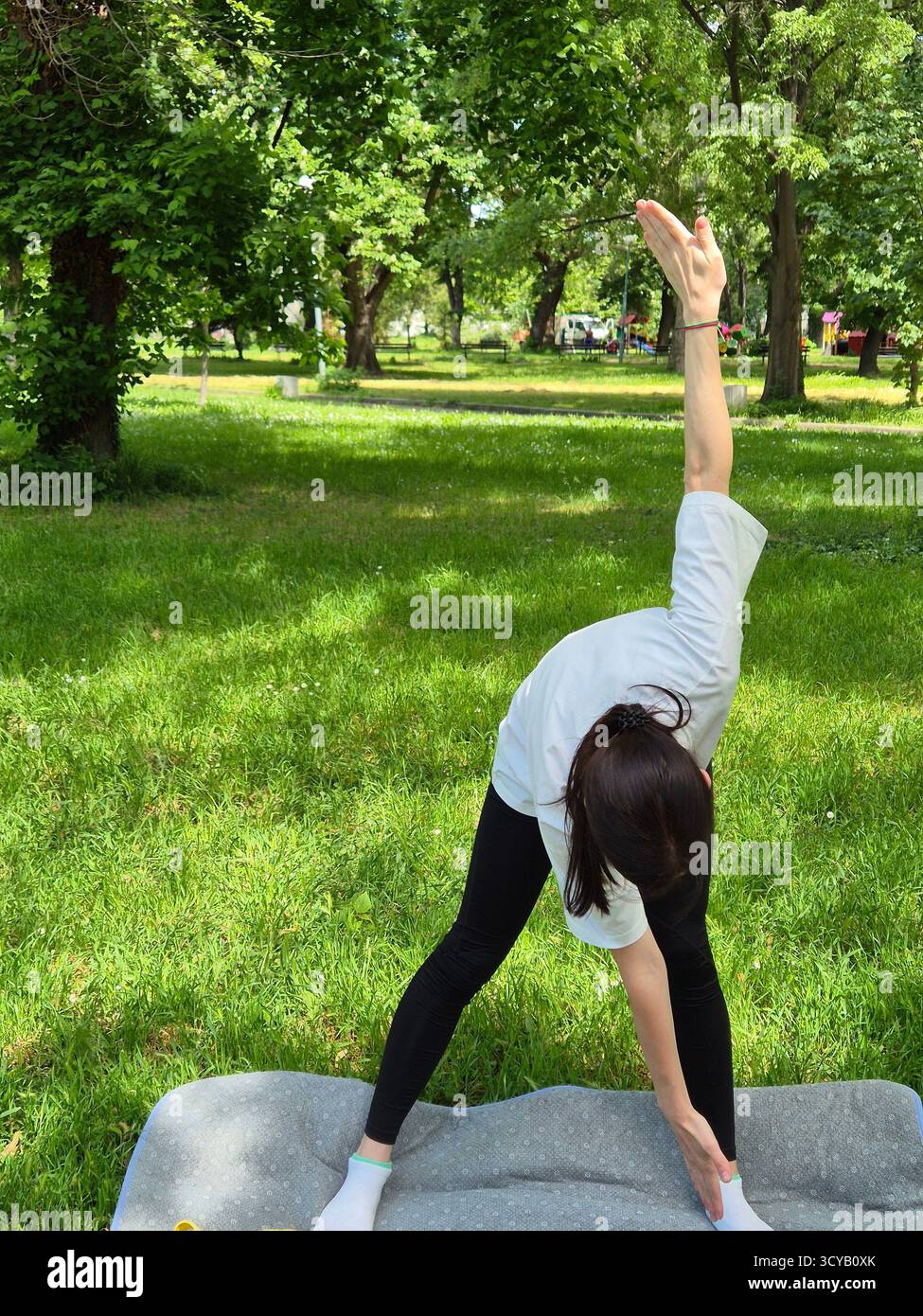 Young woman doing fitness or yoga outdoors in the park. - Smartphone Captured Stock Image