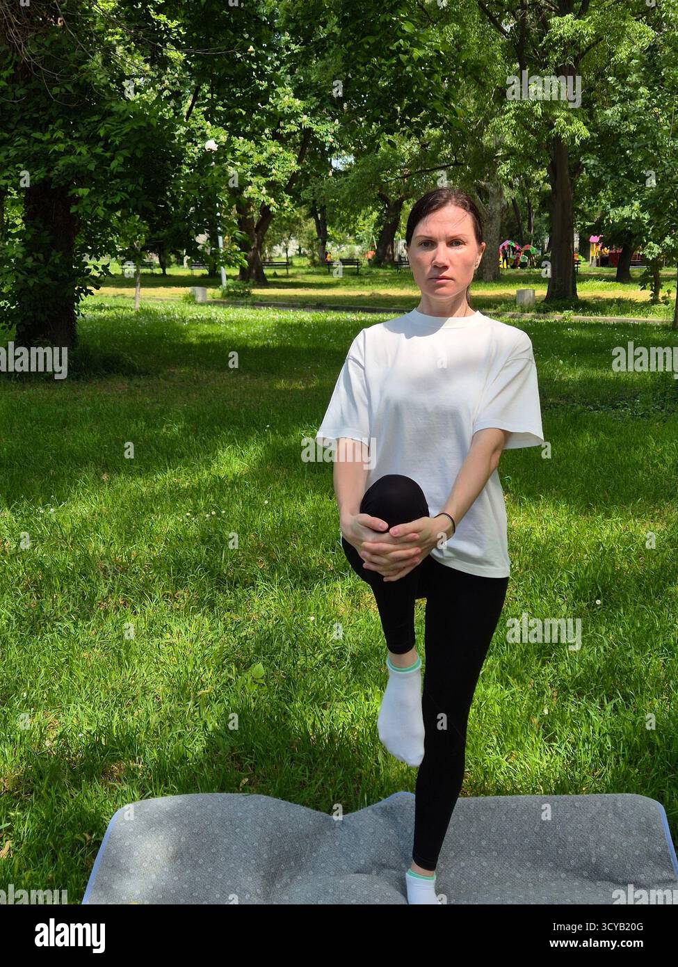 Young woman doing fitness or yoga outdoors in the park. - Smartphone Captured Stock Image
