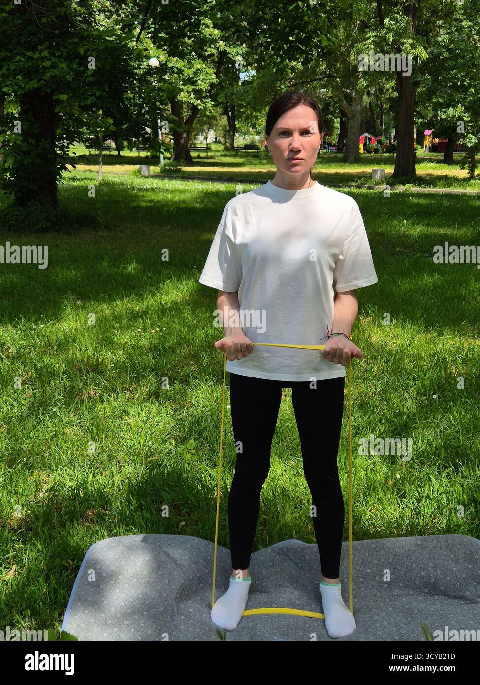Young woman doing fitness or yoga outdoors in the park. - Smartphone Captured Stock Image