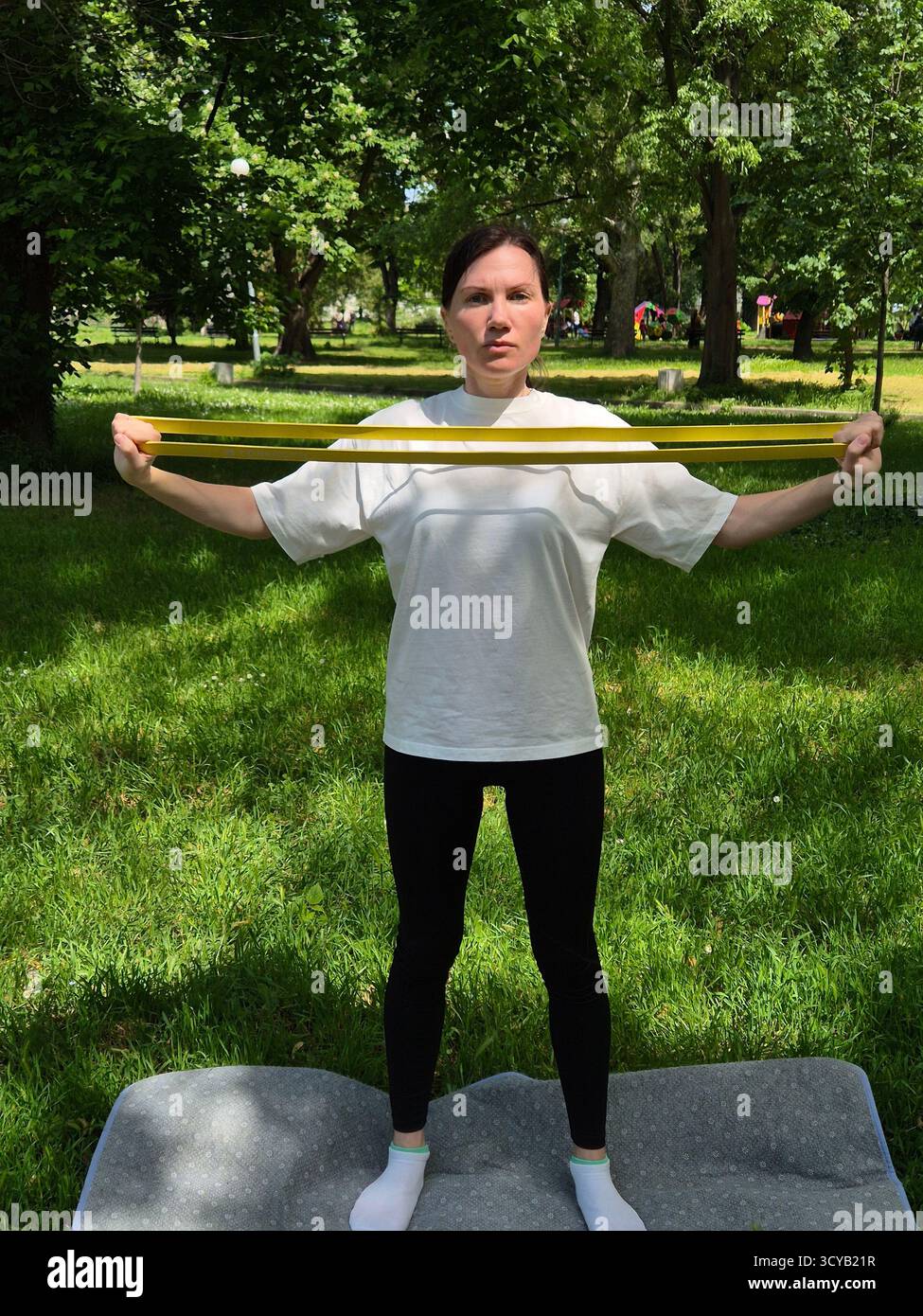 Young woman doing fitness or yoga outdoors in the park. - Smartphone Captured Stock Image
