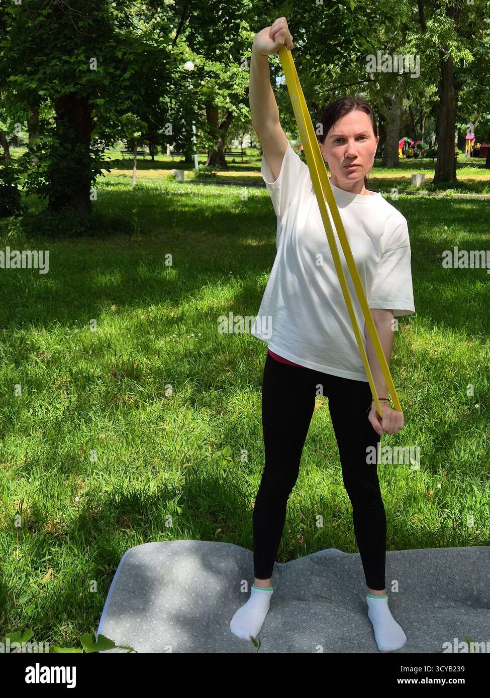 Young woman doing fitness or yoga outdoors in the park. - Smartphone Captured Stock Image