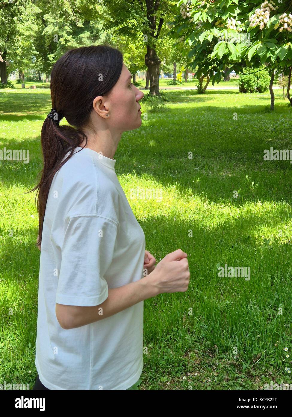 Young woman doing fitness or yoga outdoors in the park. - Smartphone Captured Stock Image