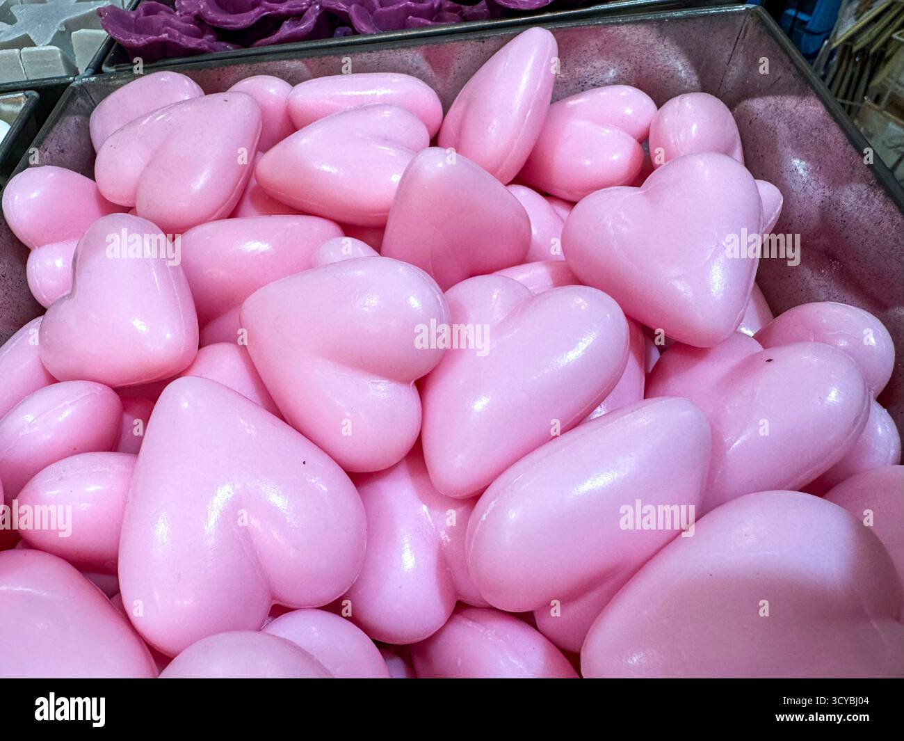 Pile of glossy pink heart-shaped soaps in a metal bin - Smartphone Captured Stock Image
