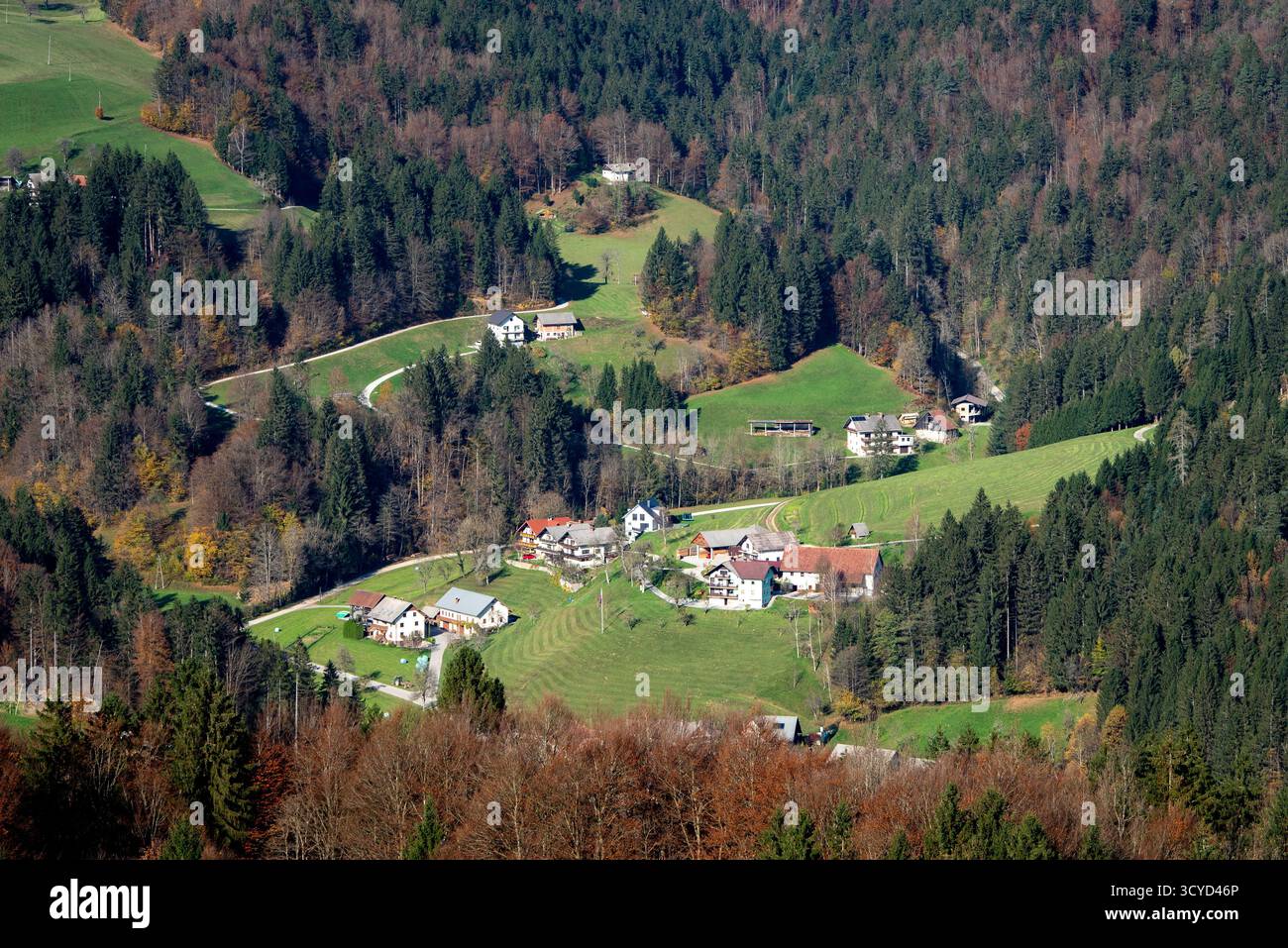 Scenic view of rolling hills, forests, and mountain peaks with a small village in the valley during autumn. Slovenia Stock Photo