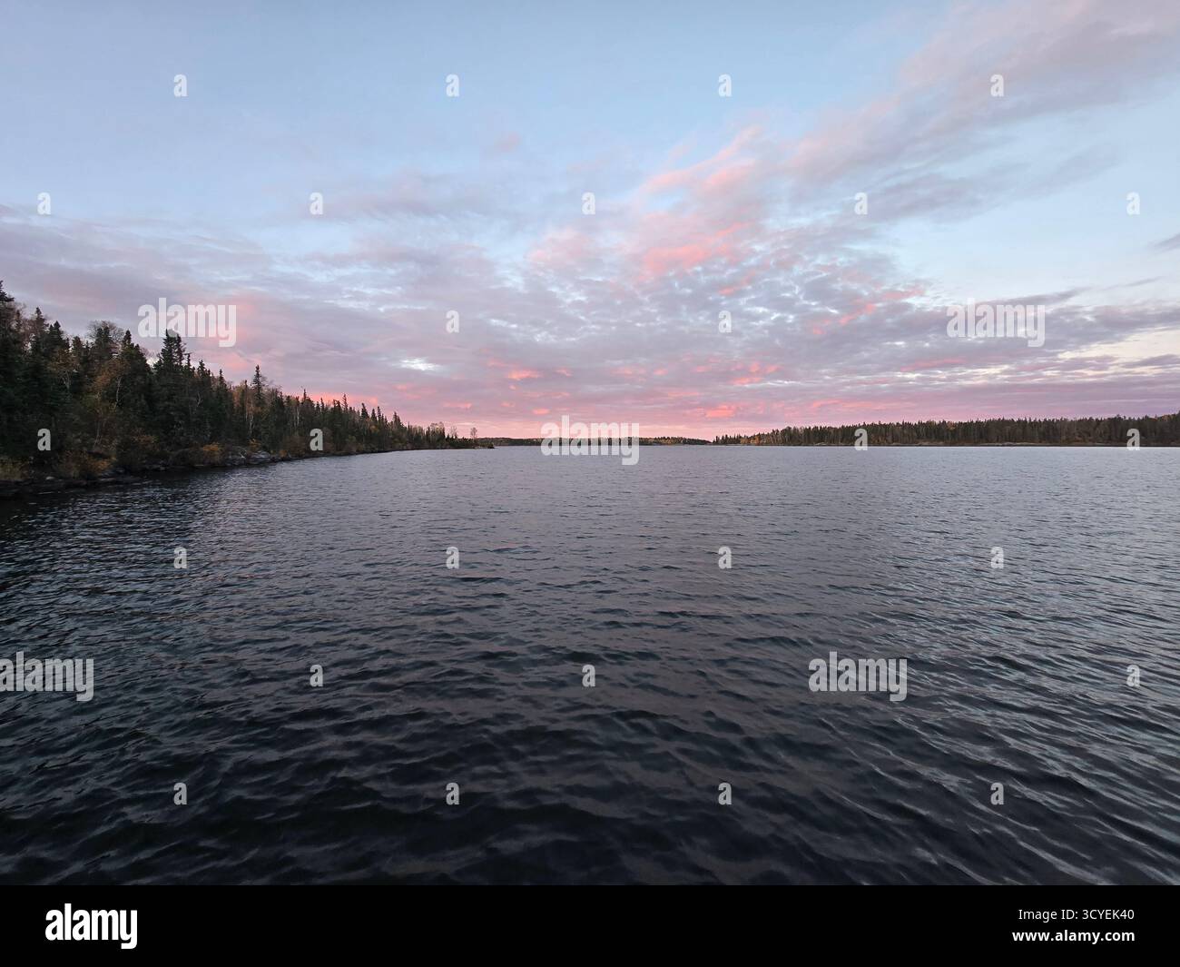 Tranquil lake sunset with colourful sky and forested shoreline. - Smartphone Captured Stock Image