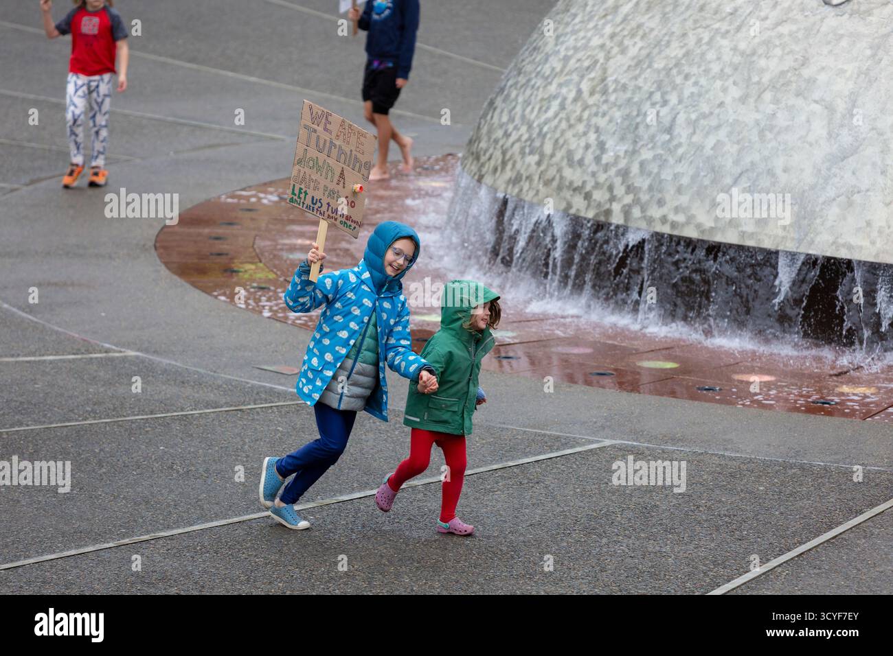 Seattle, Washington, USA. 18th October 2025. Young children run around the International Fountain holding signs during the “No Kings” protest and march. An estimated 90,000 people attended the mass protest as part of a national day of peaceful action organized by the No Kings coalition in response to perceived authoritarian actions and corruption of the Trump administration. Credit: Paul Christian Gordon/Alamy Live News Stock Photo