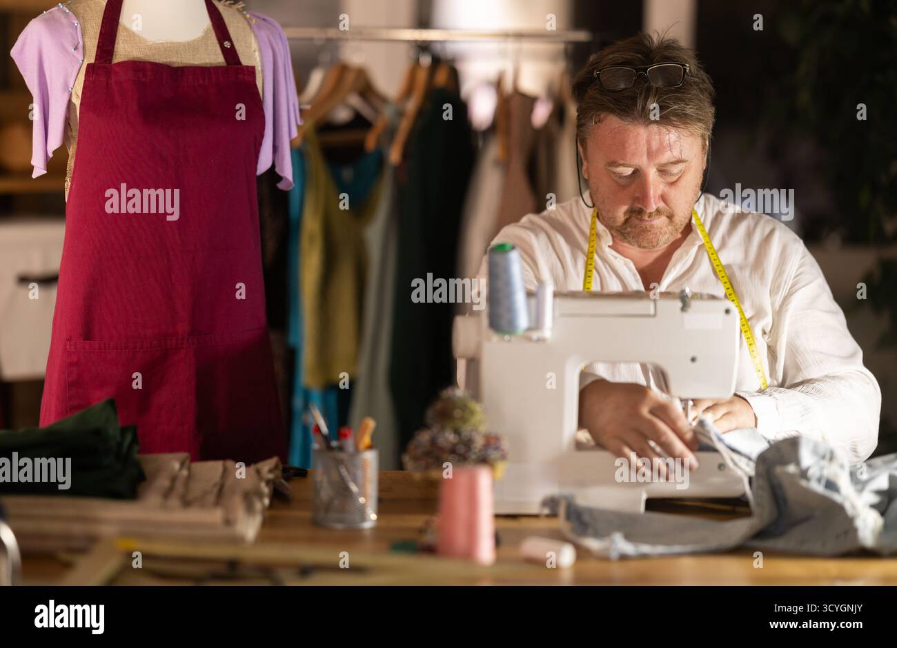 Middle-aged male dressmaker working with sewing-machine Stock Photo