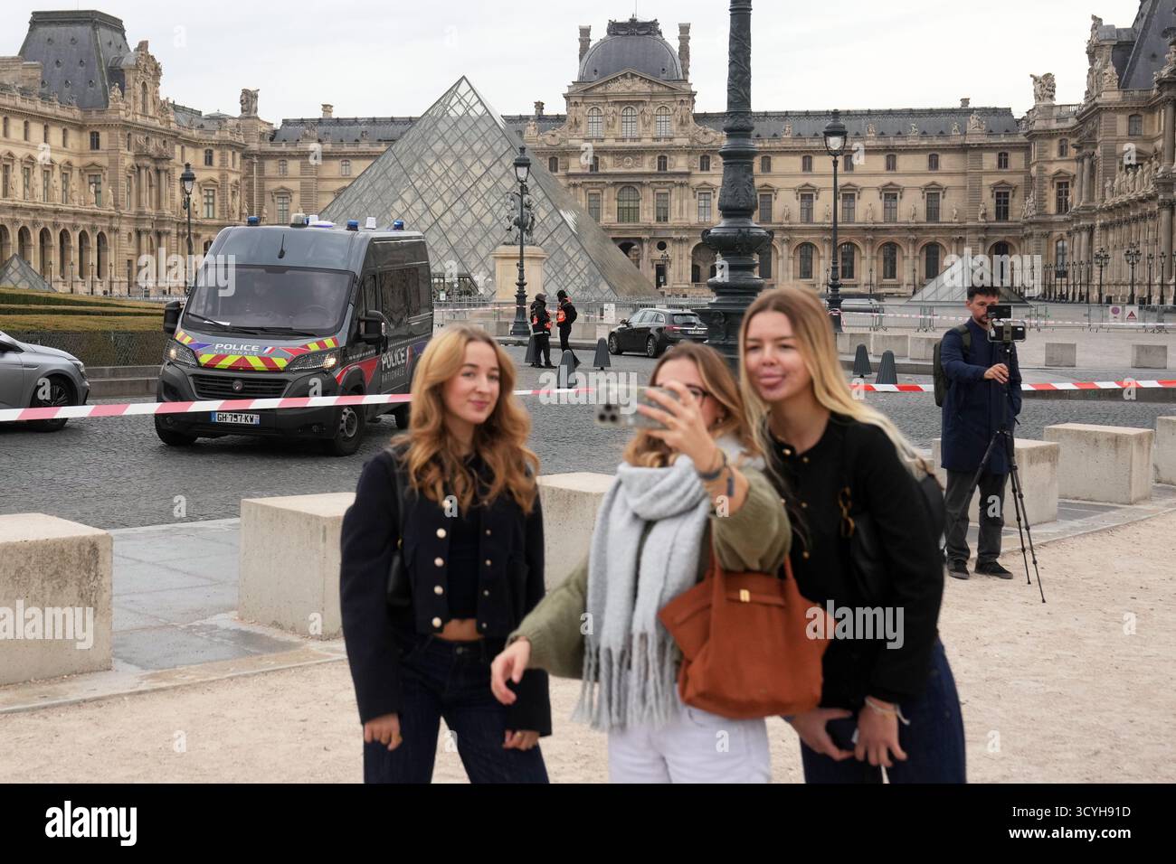 Tourists make a selfie in the courtyard of the closed Louvre museum after a robbery Sunday, Oct. 19, 2025 in Paris. (AP Photo/Thibault Camus) Stock Photo