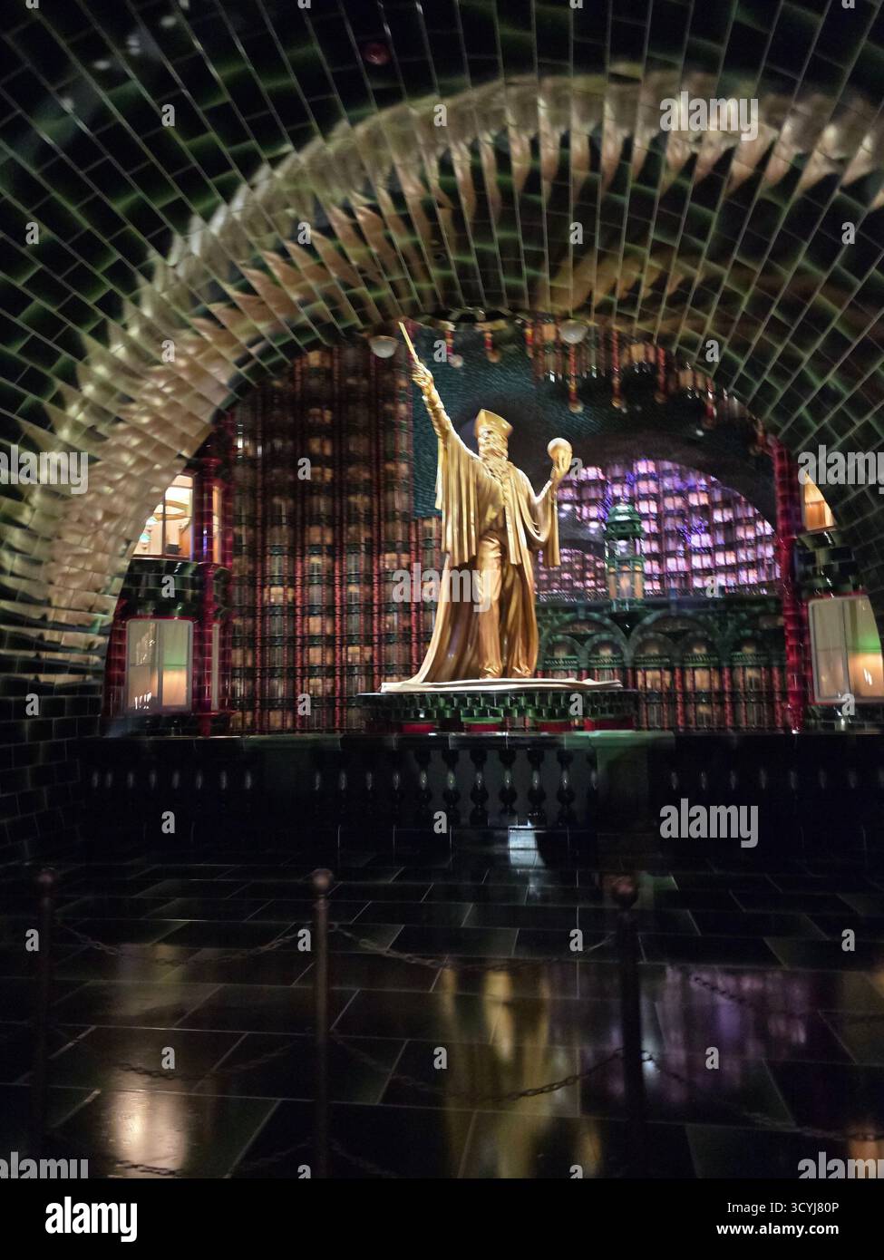 A dramatically lit interior showcasing the gold statue and intricate banking hall design inside the Magic of Ministry, Immersive, Epic Universe - Smartphone Captured Stock Image