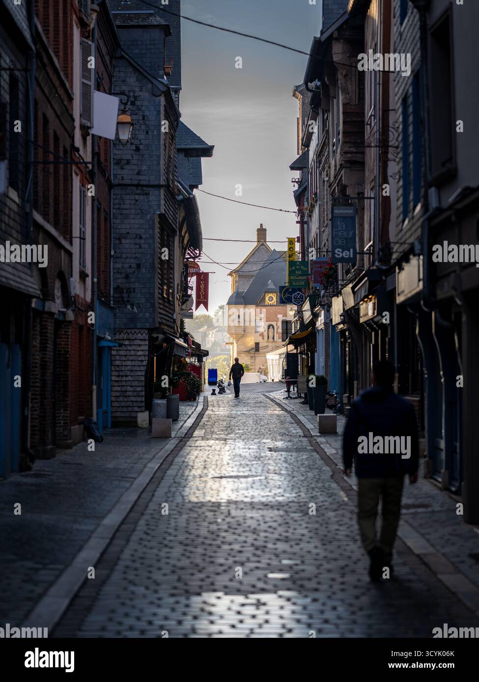 Honfleur, France - September 27, 2025: A pedestrian street at dawn with two unrecognisable men walking. Taken on a late summer morning with partly clo Stock Photo