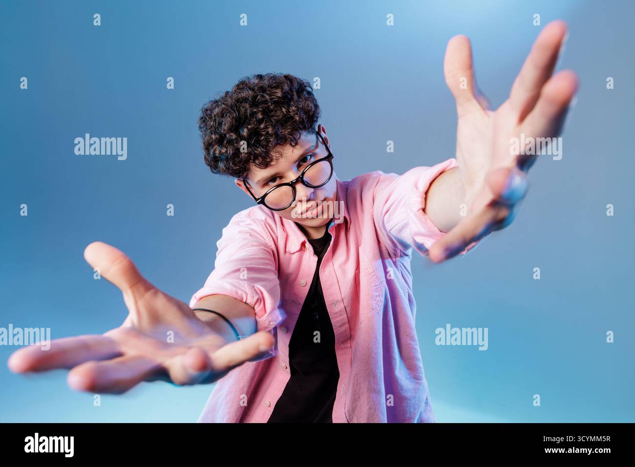 Young man with open hands and glasses inviting support or contact, ideal for charity, outreach, CTA banners and social media engagement. Stock Photo
