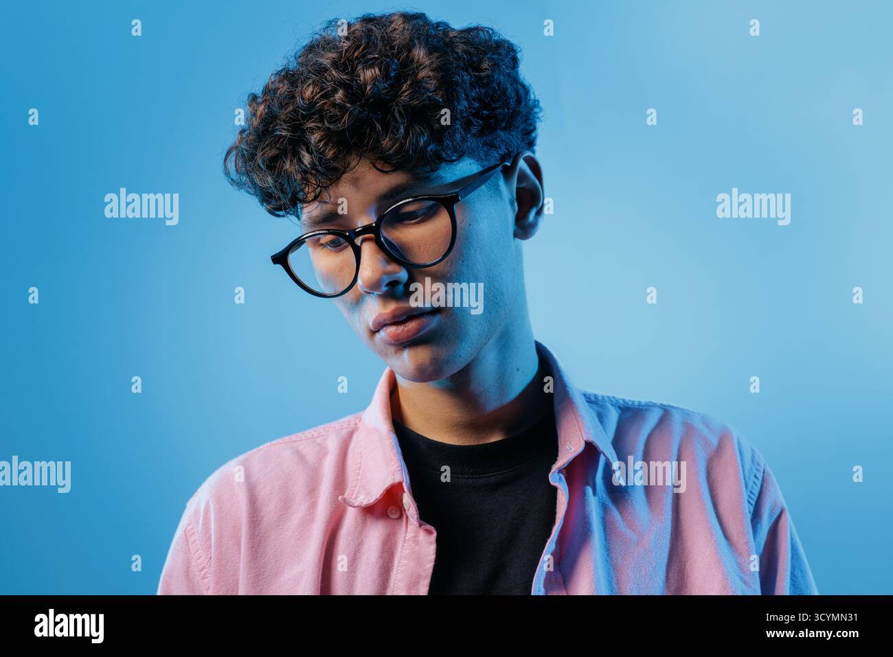 Close portrait of a thoughtful young man in glasses, ideal for mental health, stress, burnout, counseling, and wellbeing awareness projects. Stock Photo