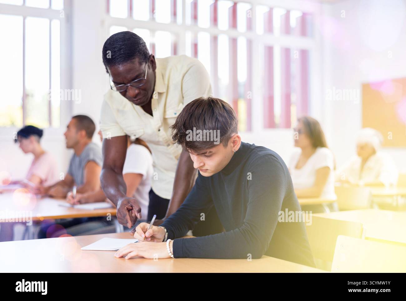 Professor explaining task solution to young man in college Stock Photo