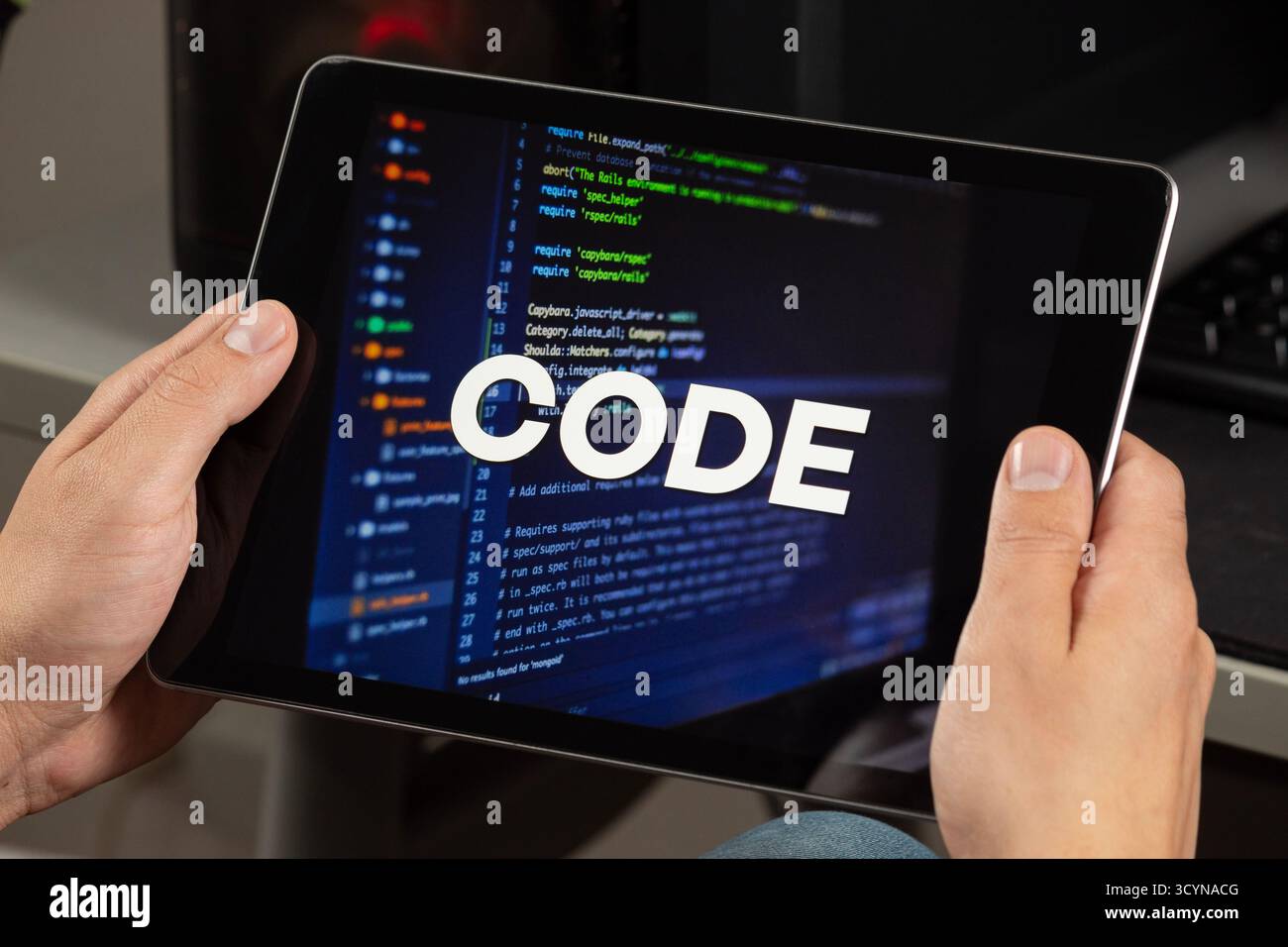 Close up to a male hands holding a tablet with the phrase code over a writing code concept Stock Photo