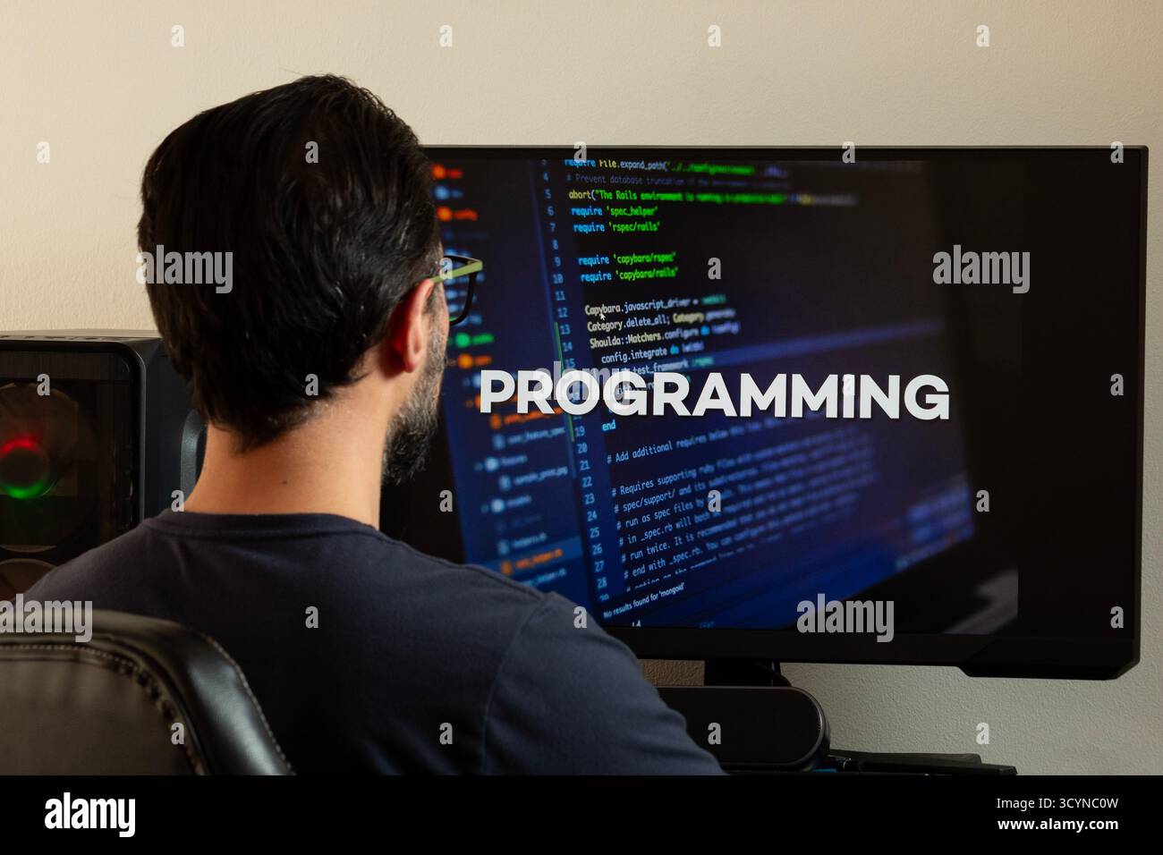 Close up to a man watching a computer screen with the word programming and a writting code concept Stock Photo
