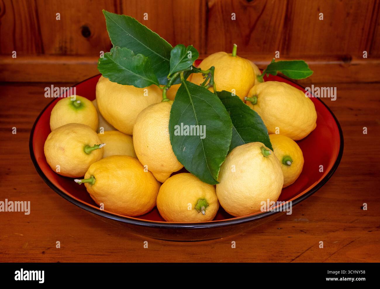 A red bowl of ripe Eureka lemons on a welsh dresser Stock Photo