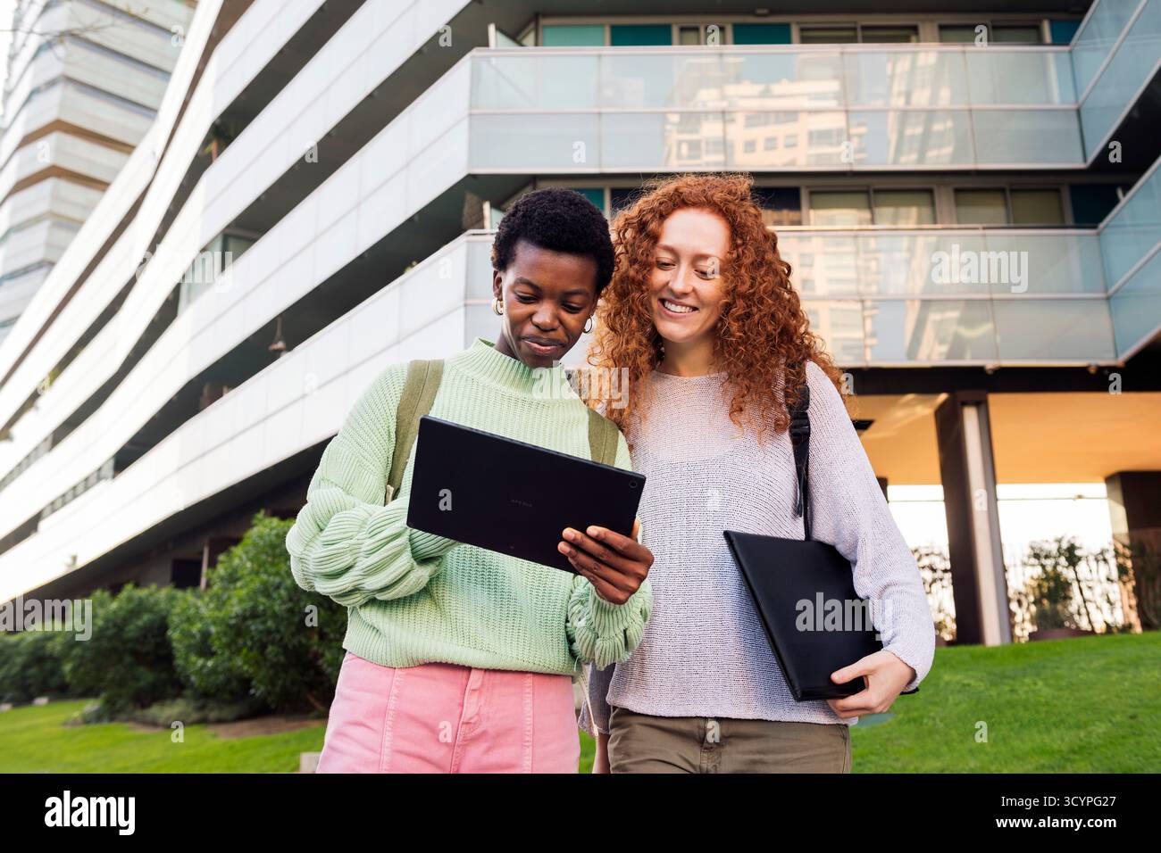 two young women smiling while using a tablet Stock Photo