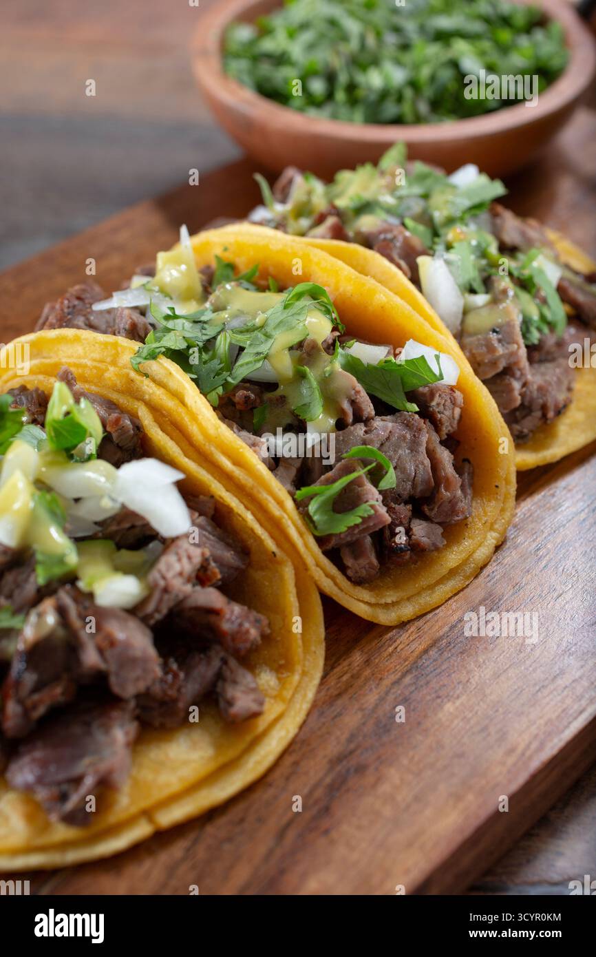 A view of three carne asada tacos on a wood tray. Stock Photo