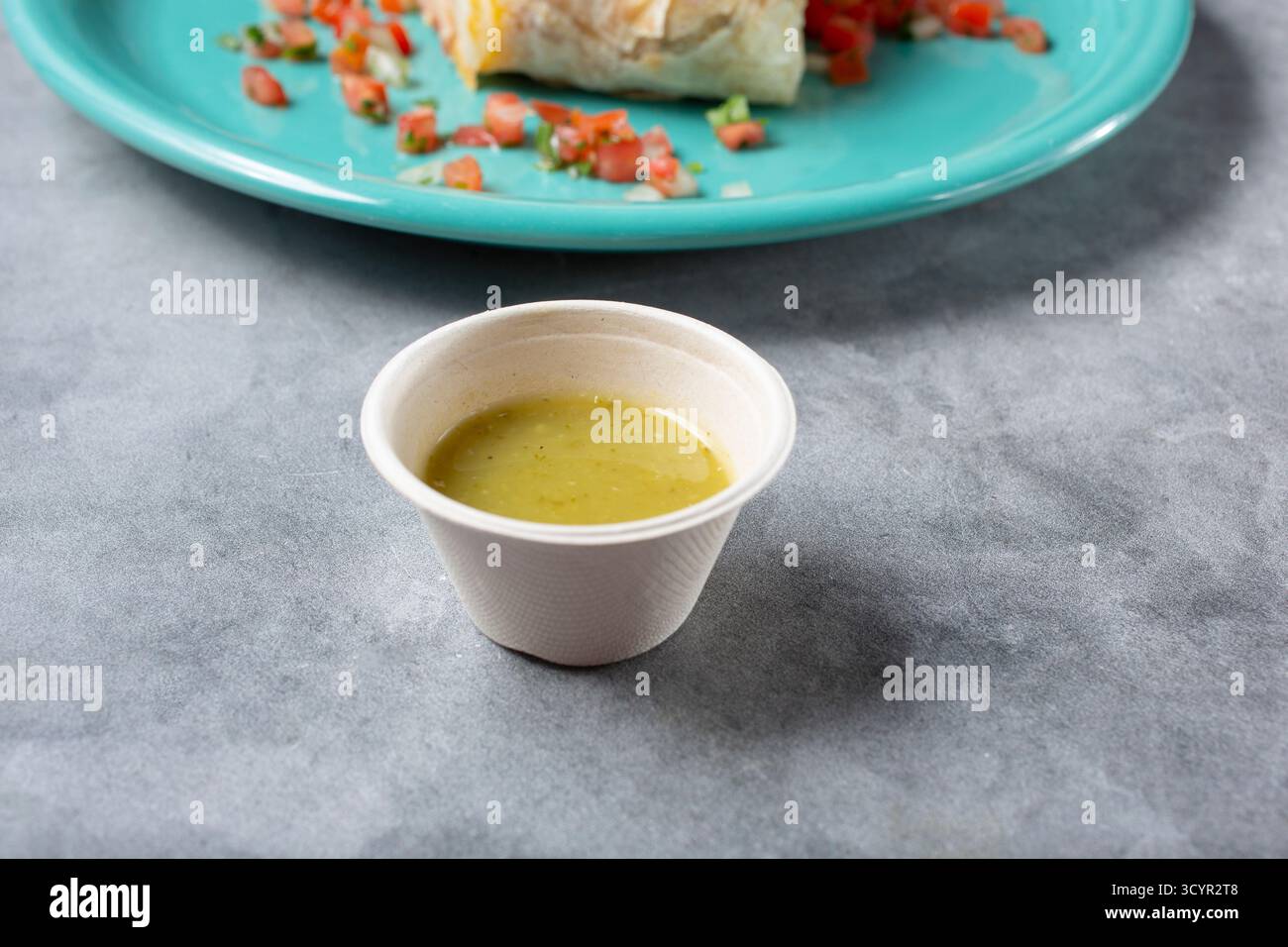 A view of a recycled paper condiment cup of salsa verde. Stock Photo