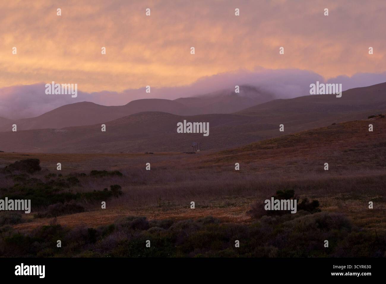 Soft pastel clouds rolling through open hill side. Stock Photo