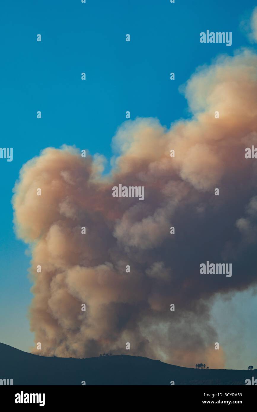 Large Smoke Plume Rising Over Mountain Sky Stock Photo