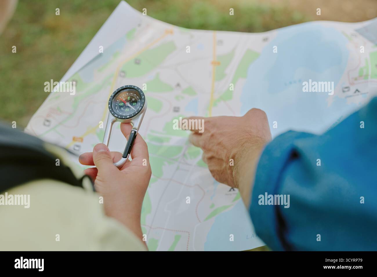 Young Adult Man Navigating Outdoors Using Compass and Paper Map Stock Photo