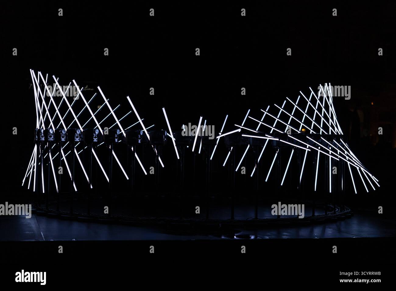 The fascinating night scene captures a modern light installation that dominates the space with a futuristic aesthetic and consists of a number of diag Stock Photo