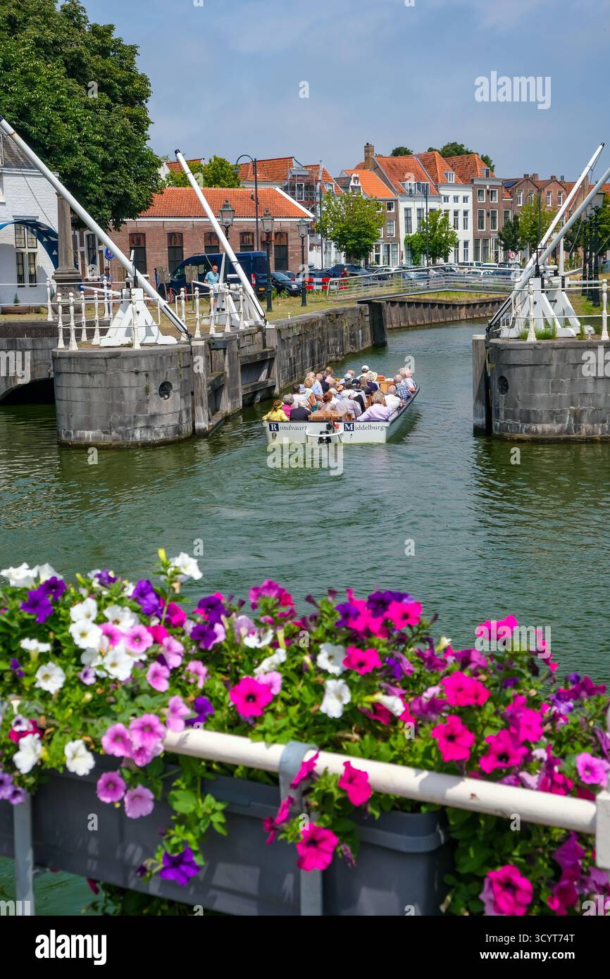 02.07.2025, Netherlands, Zeeland, Middelburg - Town houses on the Binnenhaven in the old town. Tourists take a boat trip through the canals of the old Stock Photo